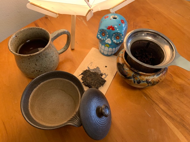 A gaiwan brewing vessel, compressed pu'erh tea, and my usual cup with brew basket